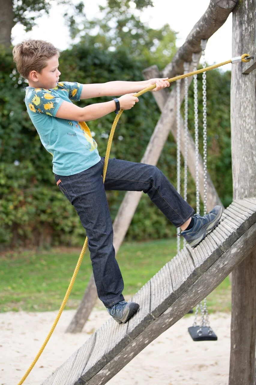 A boy wearing jeans and a t-shirt, climbing.