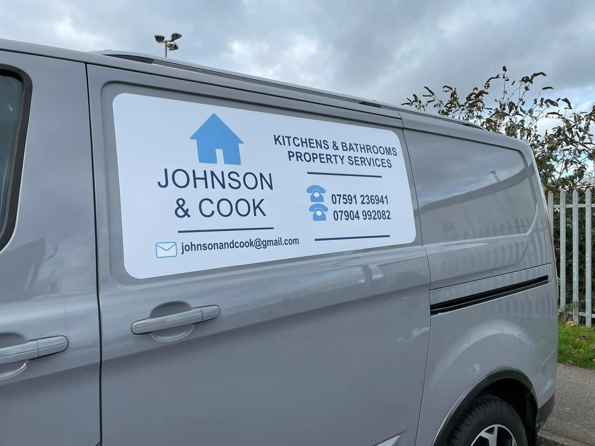 Grey van with a large advertisement sign on the side for Johnson & Cook, offering kitchen and bathroom property services, with contact details and email.