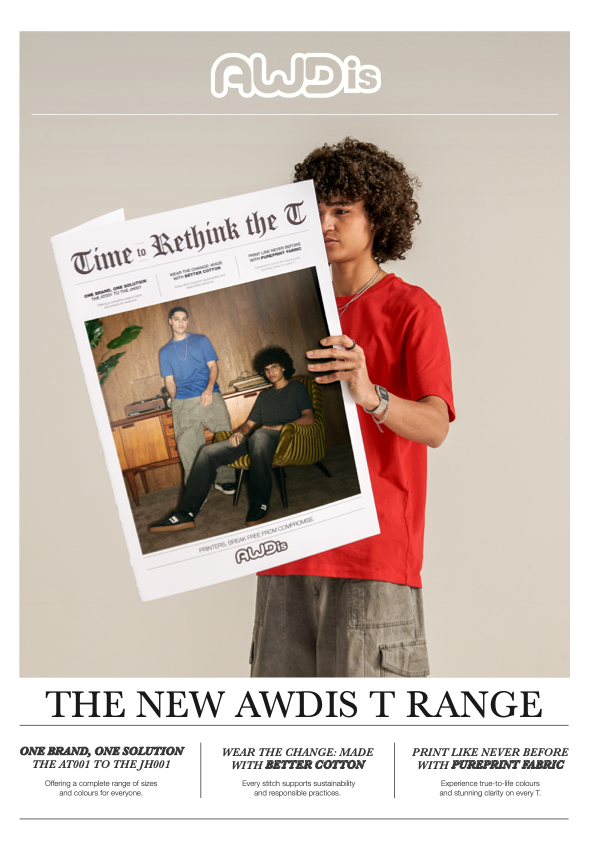 A young man with curly hair wearing a red t-shirt and cargo shorts holding a newspaper styled as a newspaper front page, with the headline 'The New AWDis T Range' and a photo of two people sitting and standing in a room.