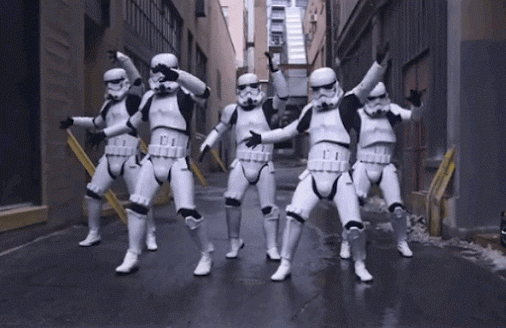 Five people in stormtrooper costumes dancing in an alleyway.