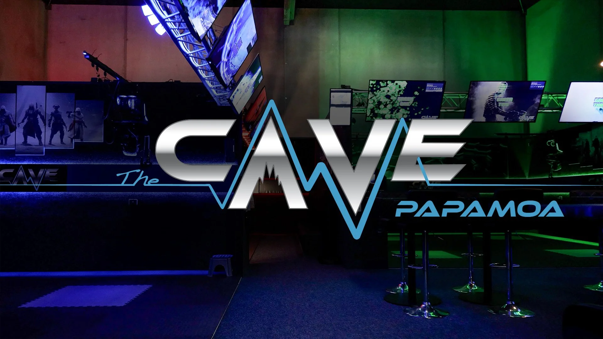 Interior of The Cave Papamoa, displaying gaming screens and a modern, colorful lighting setup, with large logo text in the foreground.