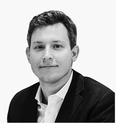 Black and white professional headshot of a man with short dark hair, wearing a suit jacket and white shirt