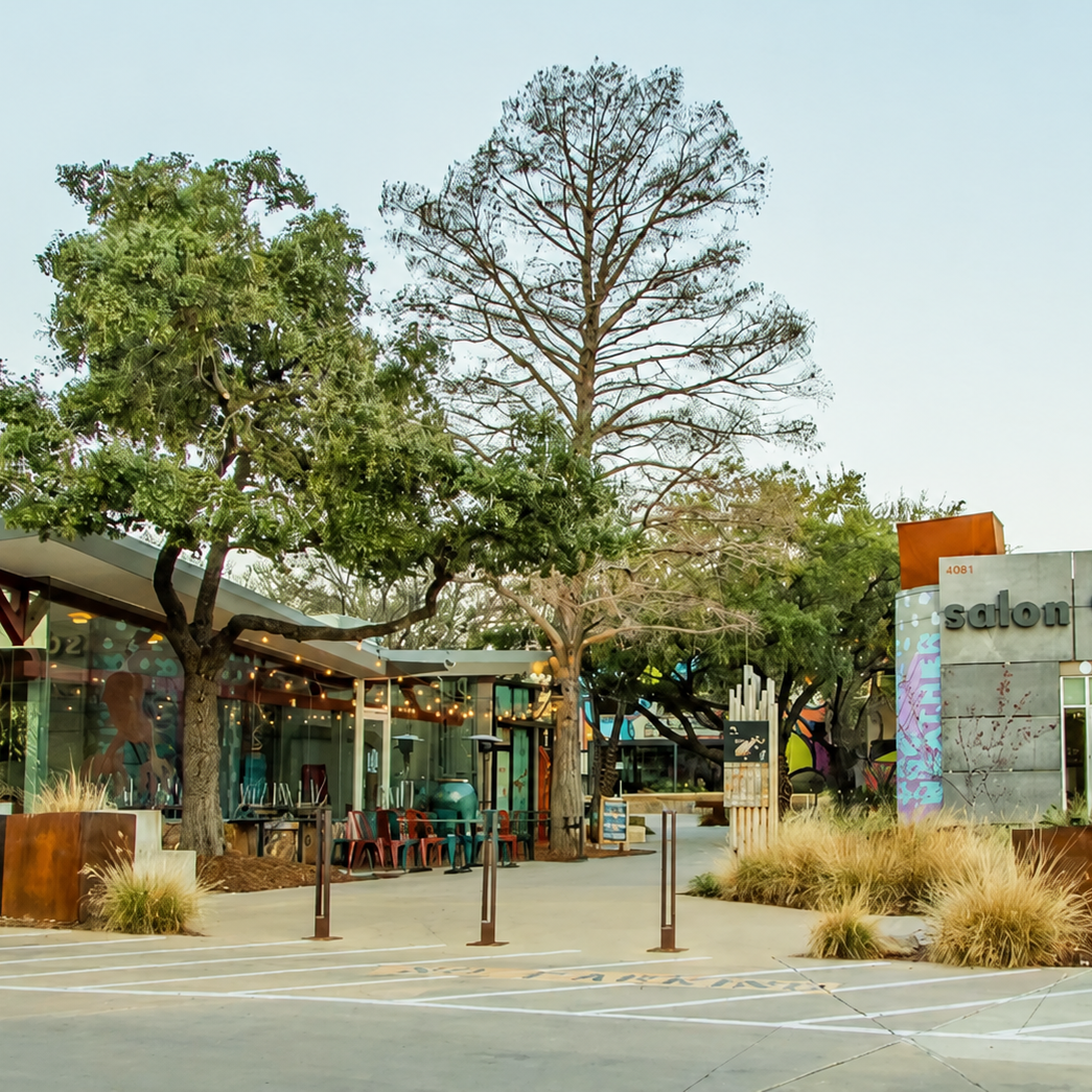 Outdoor patio area with seating, trees, and a modern building with a sign that says 'salon'.