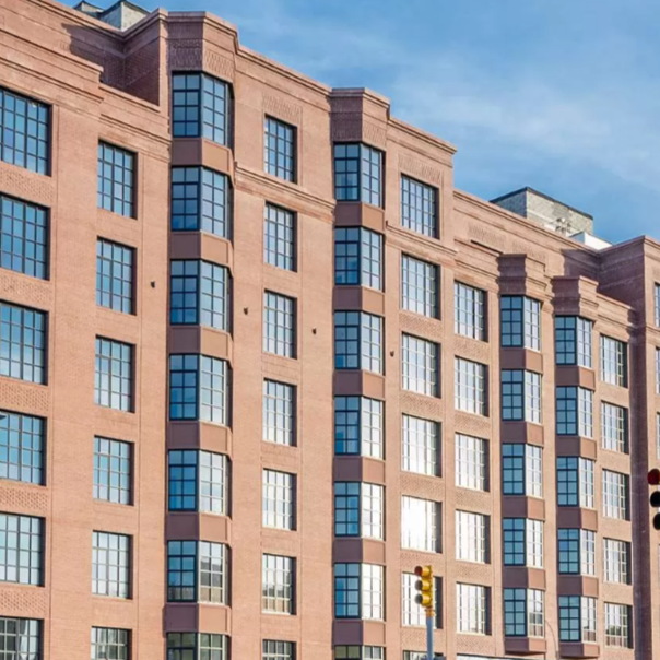 A pink brick multi-story building with large blue-tinted windows, under a clear blue sky.