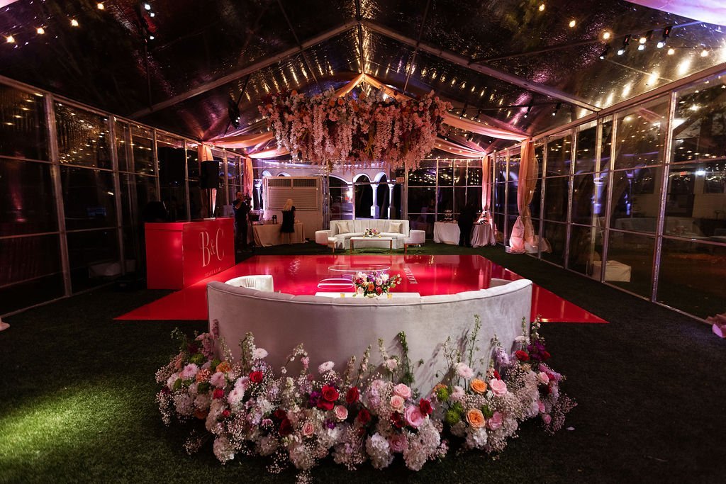 a couple's table at a wedding reception. The dance floor is behind the table, all lit in red