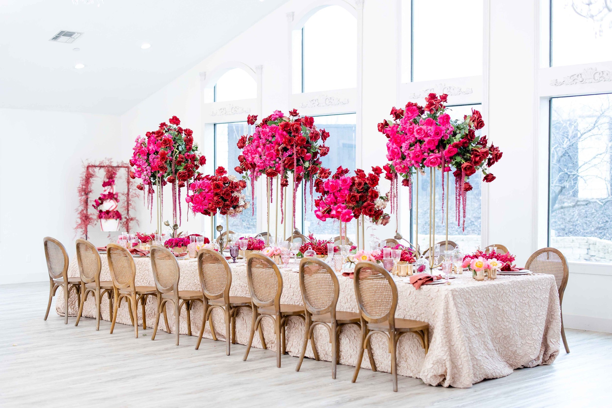 a beautifully styled head table with vineyard chairs, and bright pink flower arrangements