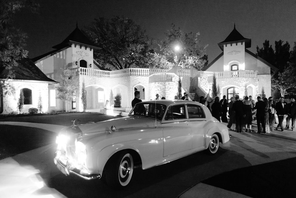a black and white image of a vintage car wiht headlights on in front of Brighton Abbey wedding venue