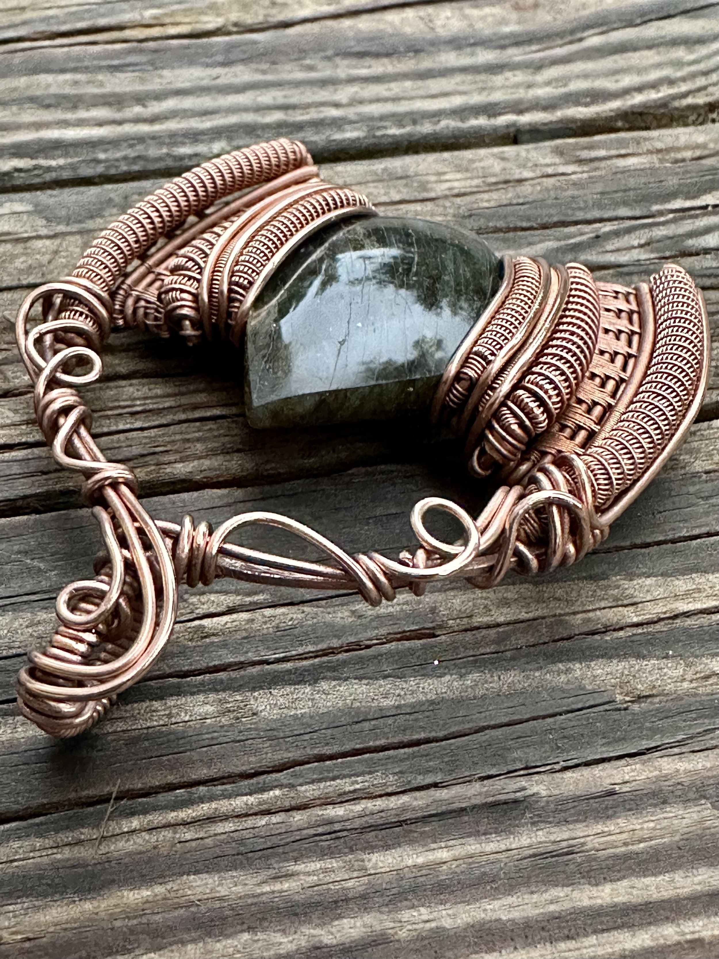 close-up view of iridescent labradorite stone intricately wrapped in copper wire showcasing the pendants detailed craftsmanship