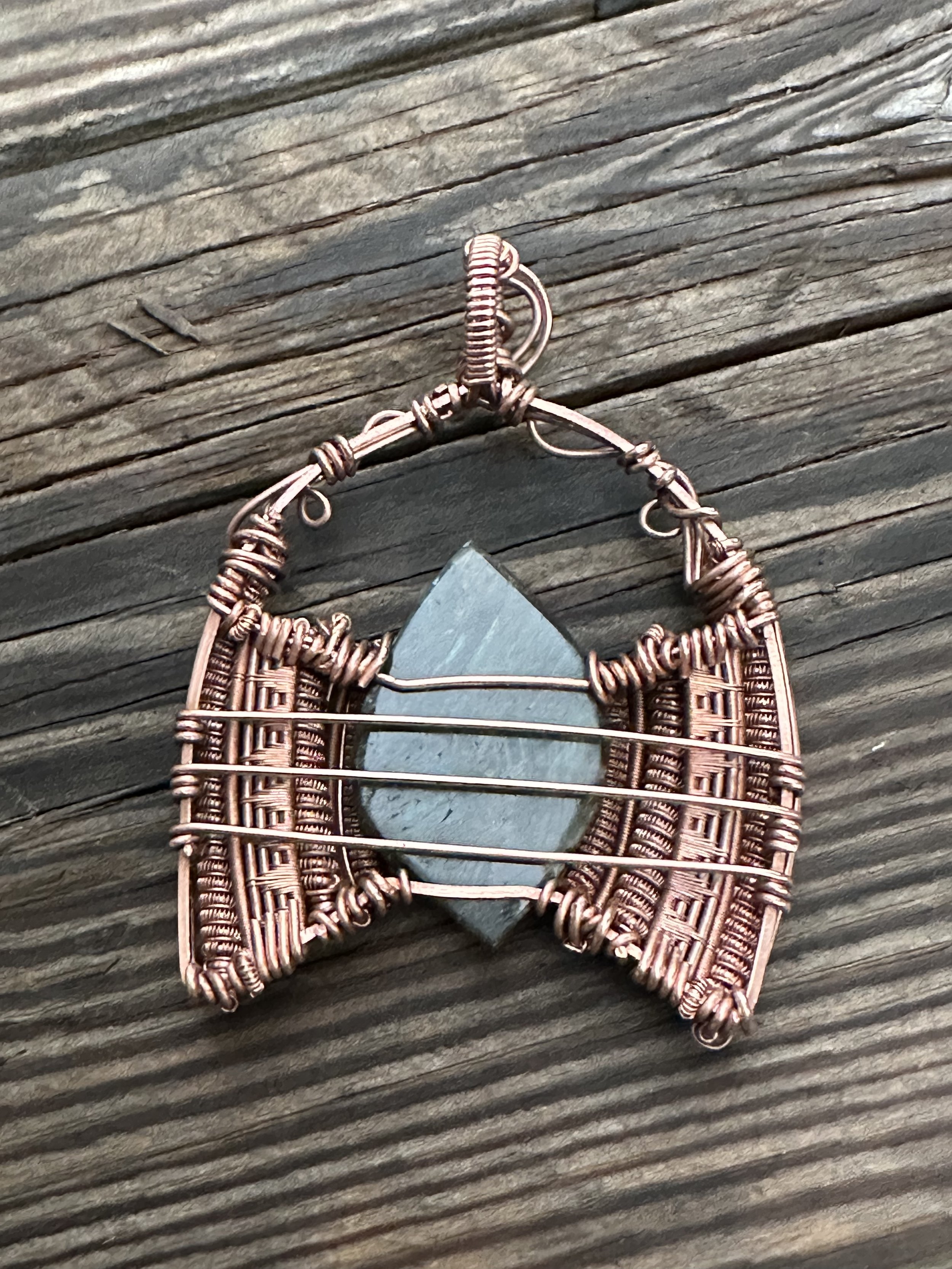 close-up view of iridescent labradorite stone intricately wrapped in copper wire showcasing the pendants detailed craftsmanship