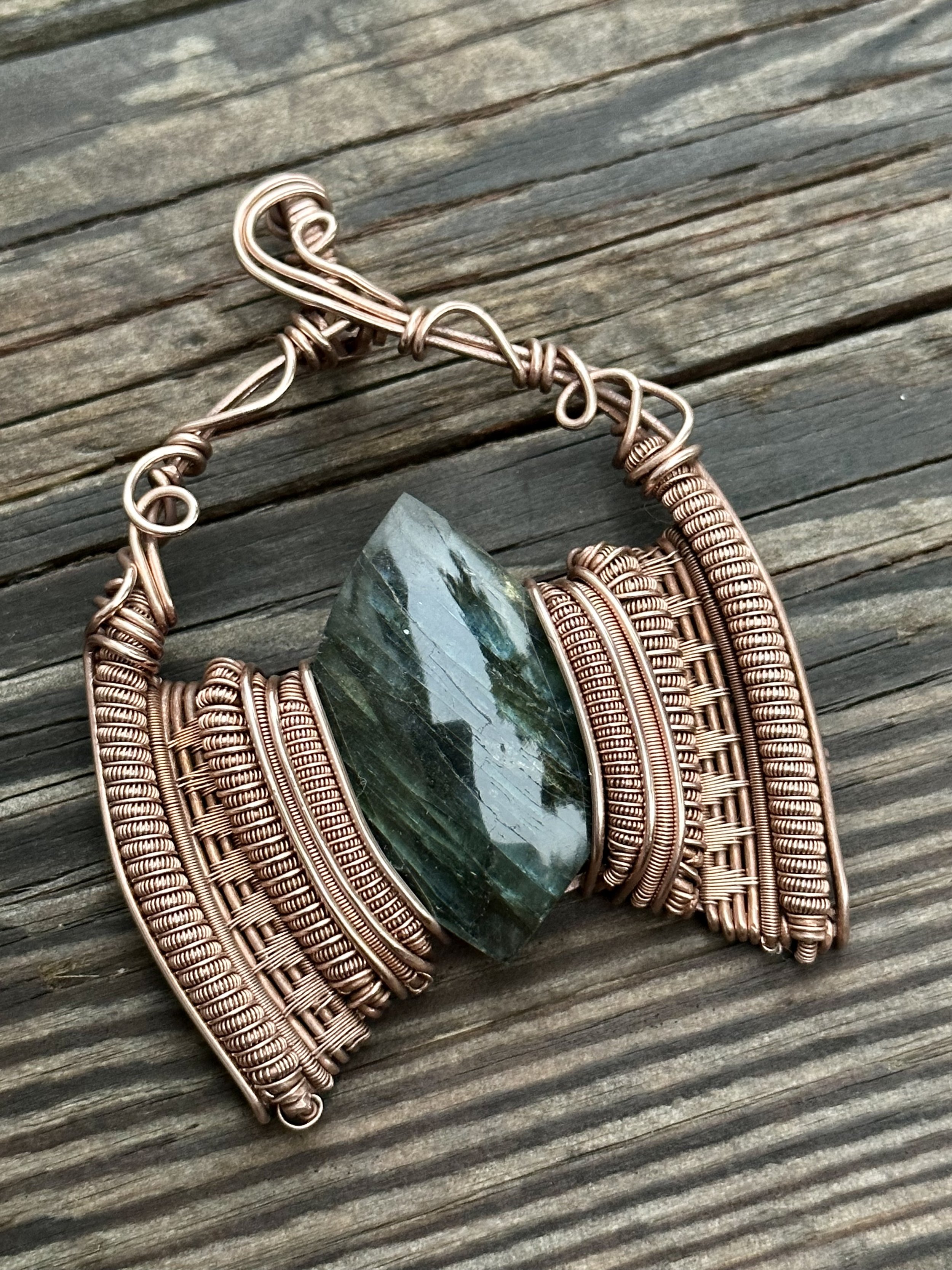 iridescent labradorite stone intricately wrapped in copper wire showcasing the pendants detailed craftsmanship