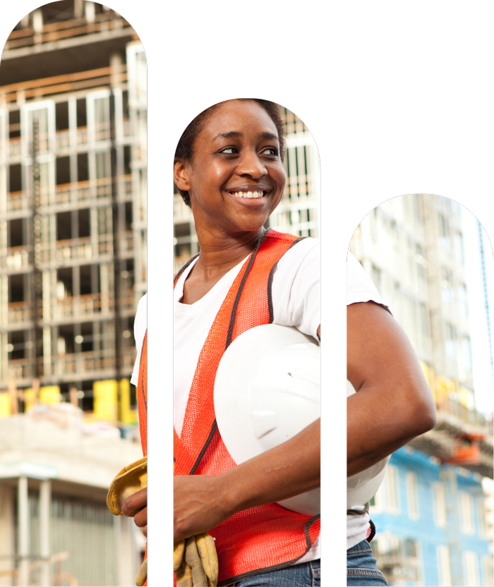 Smiling woman construction worker holding a white hard hat and safety gloves at a building site in an urban area.