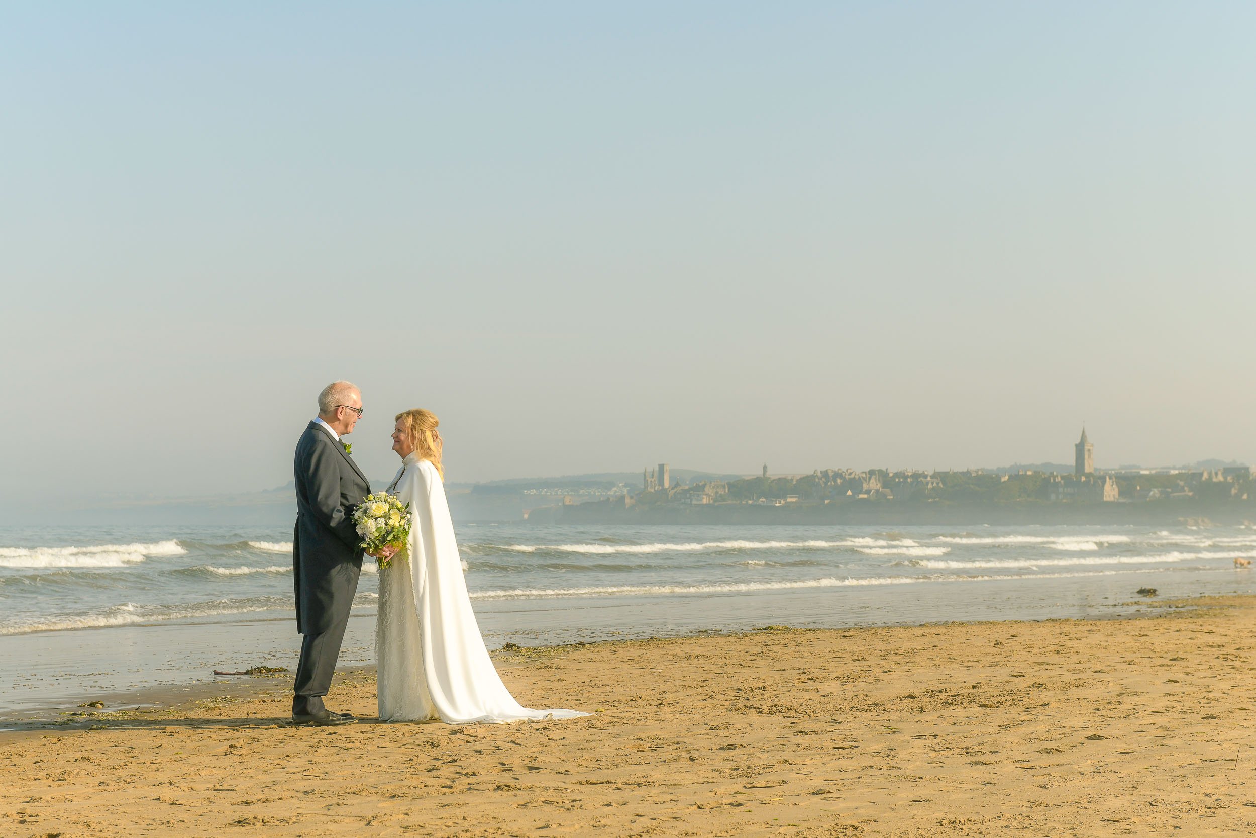 The wedding couple on the beach at St. Andrew's shortly after getting married at The Old Course Hotel.