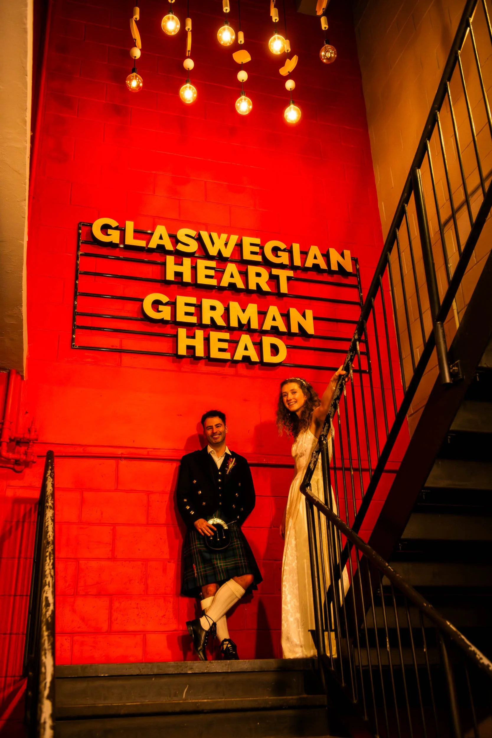West Brewery wedding photography with the newlyweds underneath the iconic 'Glaswegian Heart German Head' sign.