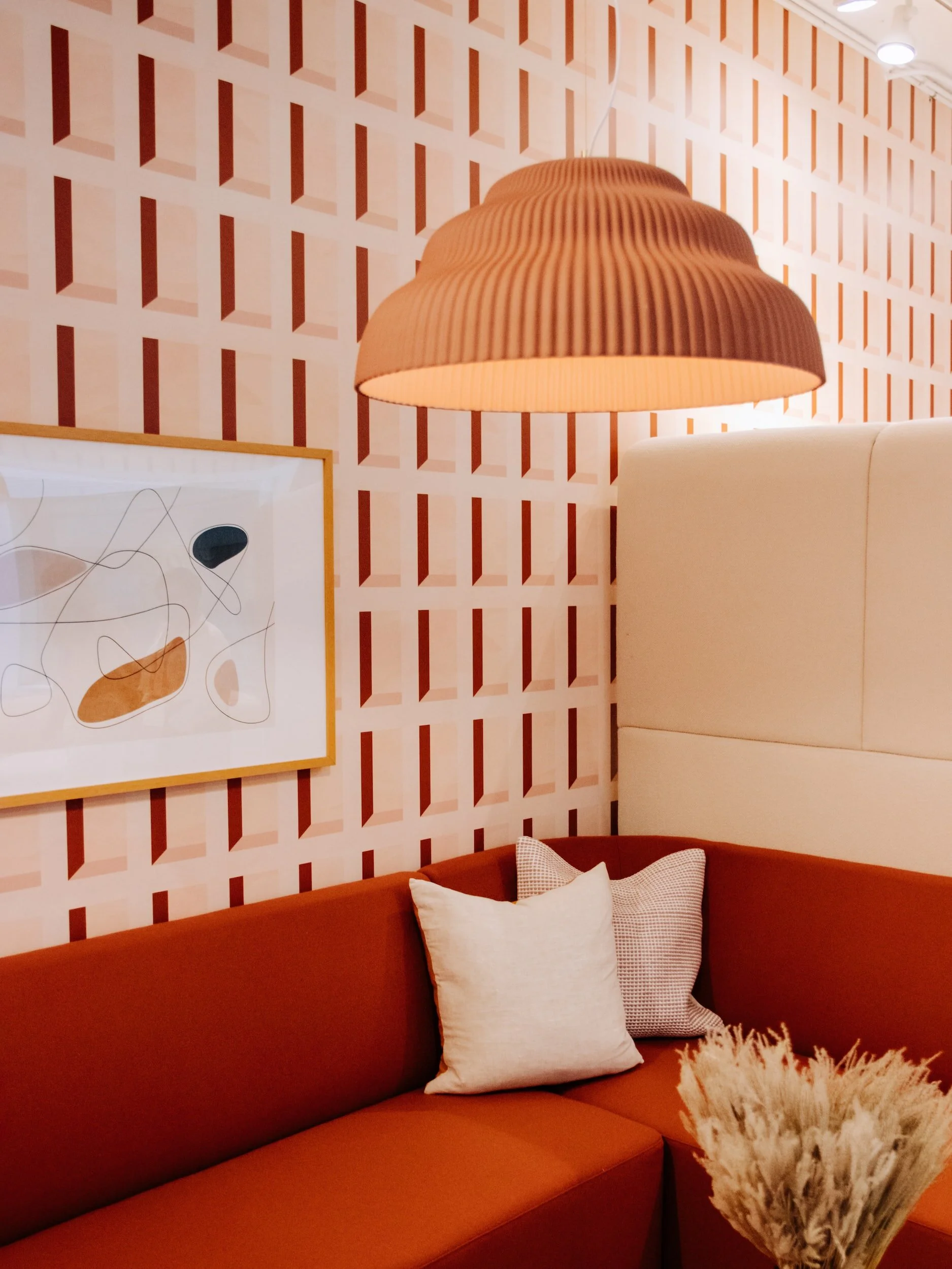 Modern living room with red couch, geometric wallpaper, and pendant lamp