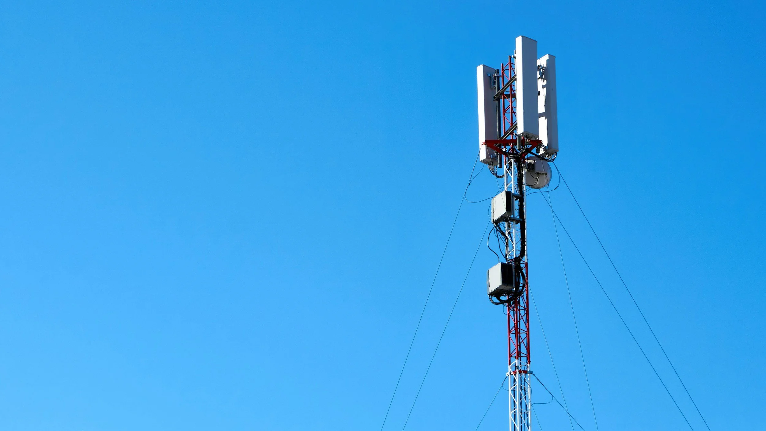A cell tower against a bright blue sky