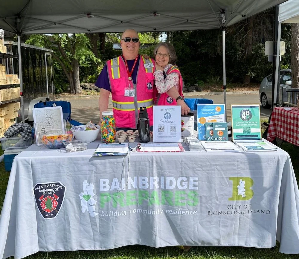 BP Volunteers standing behind the information table at the Farmers' Market