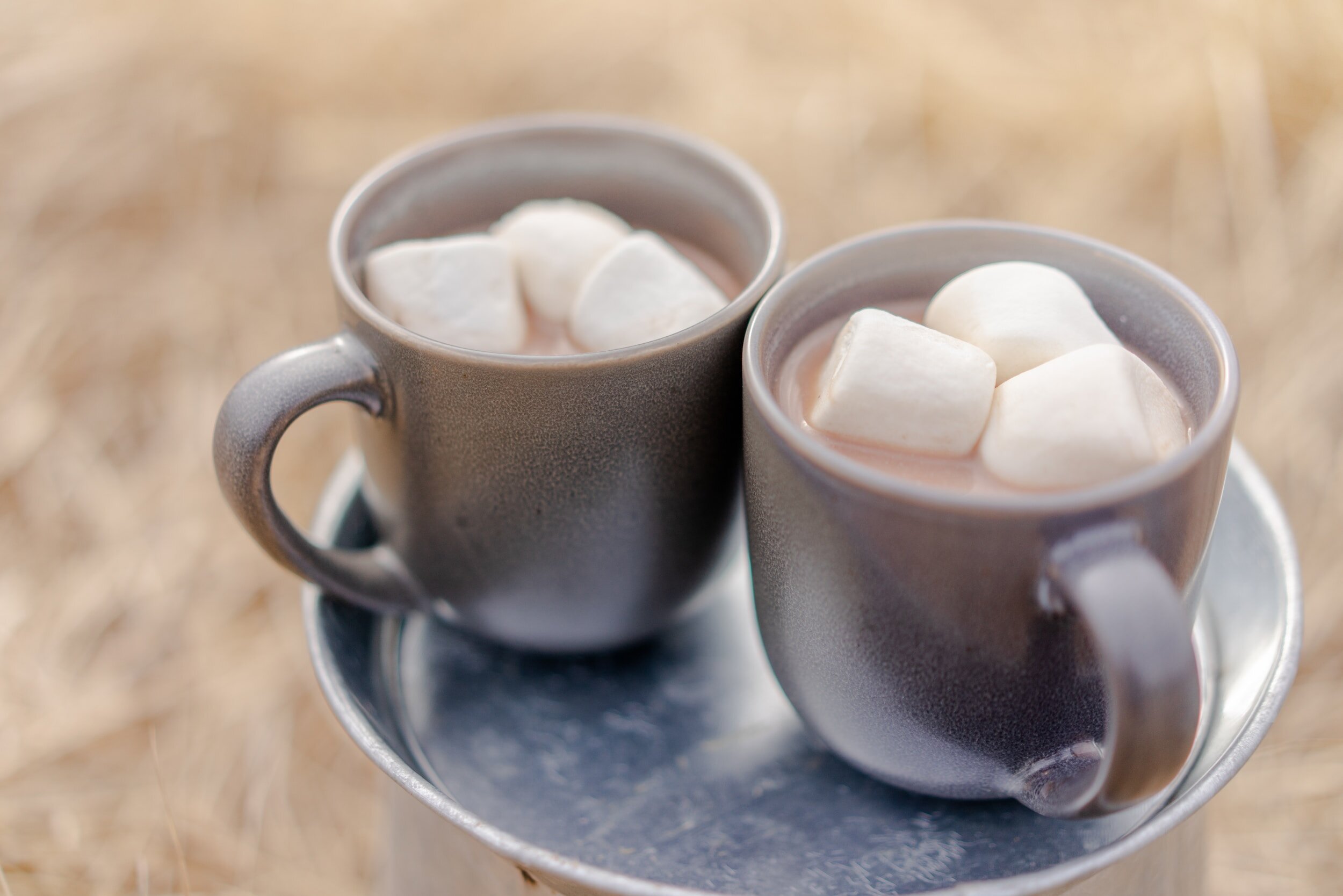 Two mugs of hot chocolate with three large marshmallows in each
