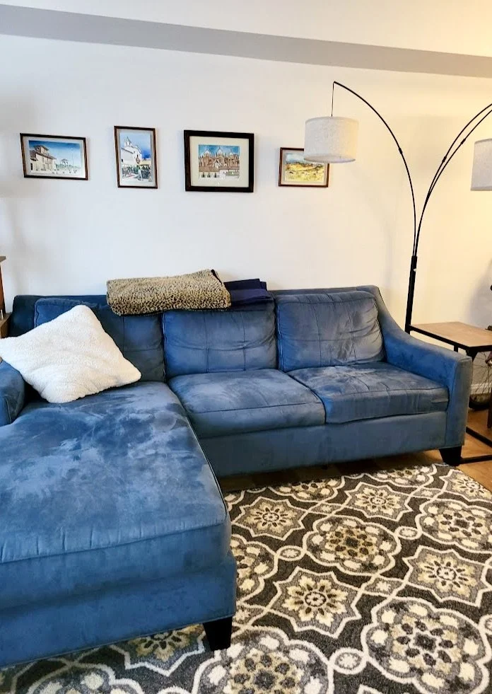 Blue, living room sofa with a standing lamp and four paintings