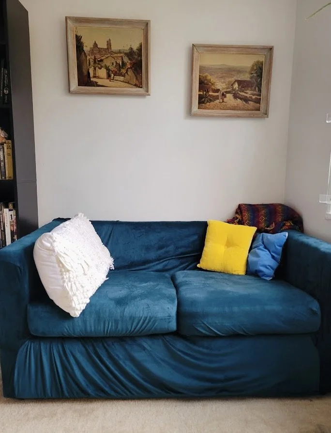 Small sofa with cheap cover and two paintings on the wall