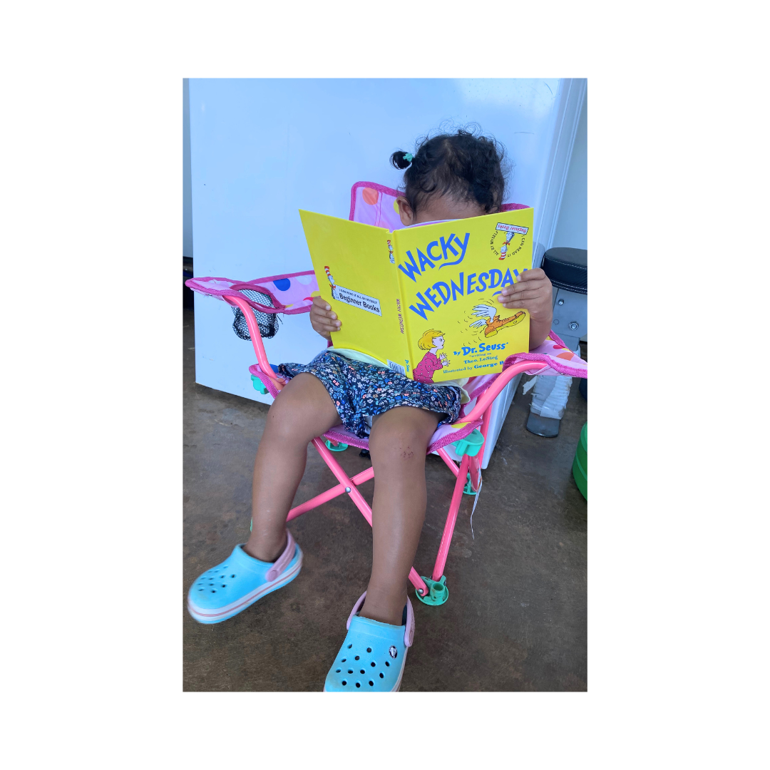 Toddler reading a book from a 12–24 month book and plushie collection