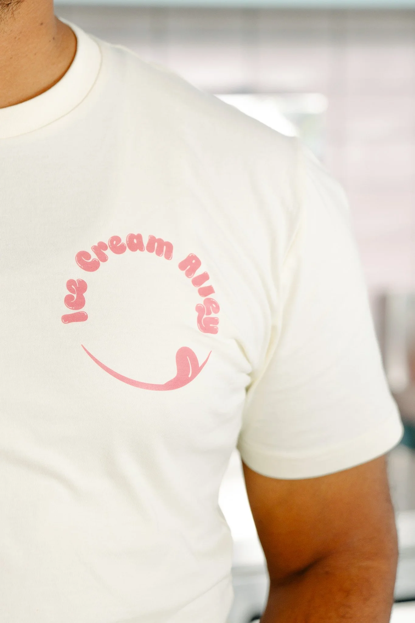 Close-up of a person's white T-shirt with pink text and a graphic that says 'Ice Cream Mommy' and a pink swirl beneath it.