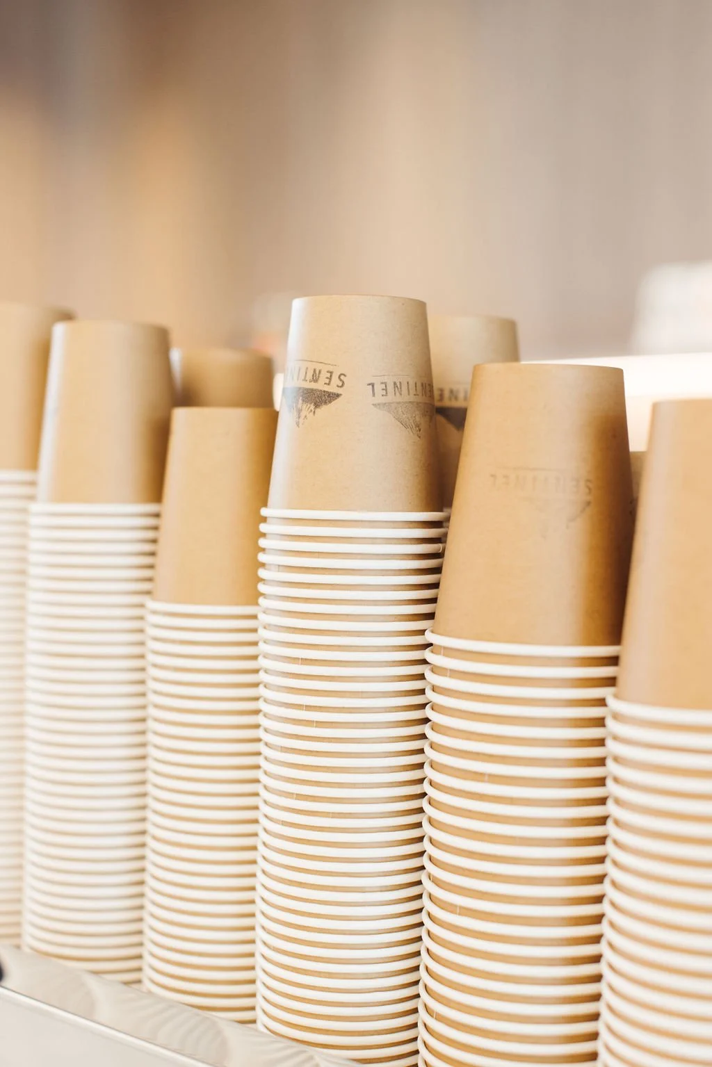 Stacked paper coffee cups with brown sleeves in a row.