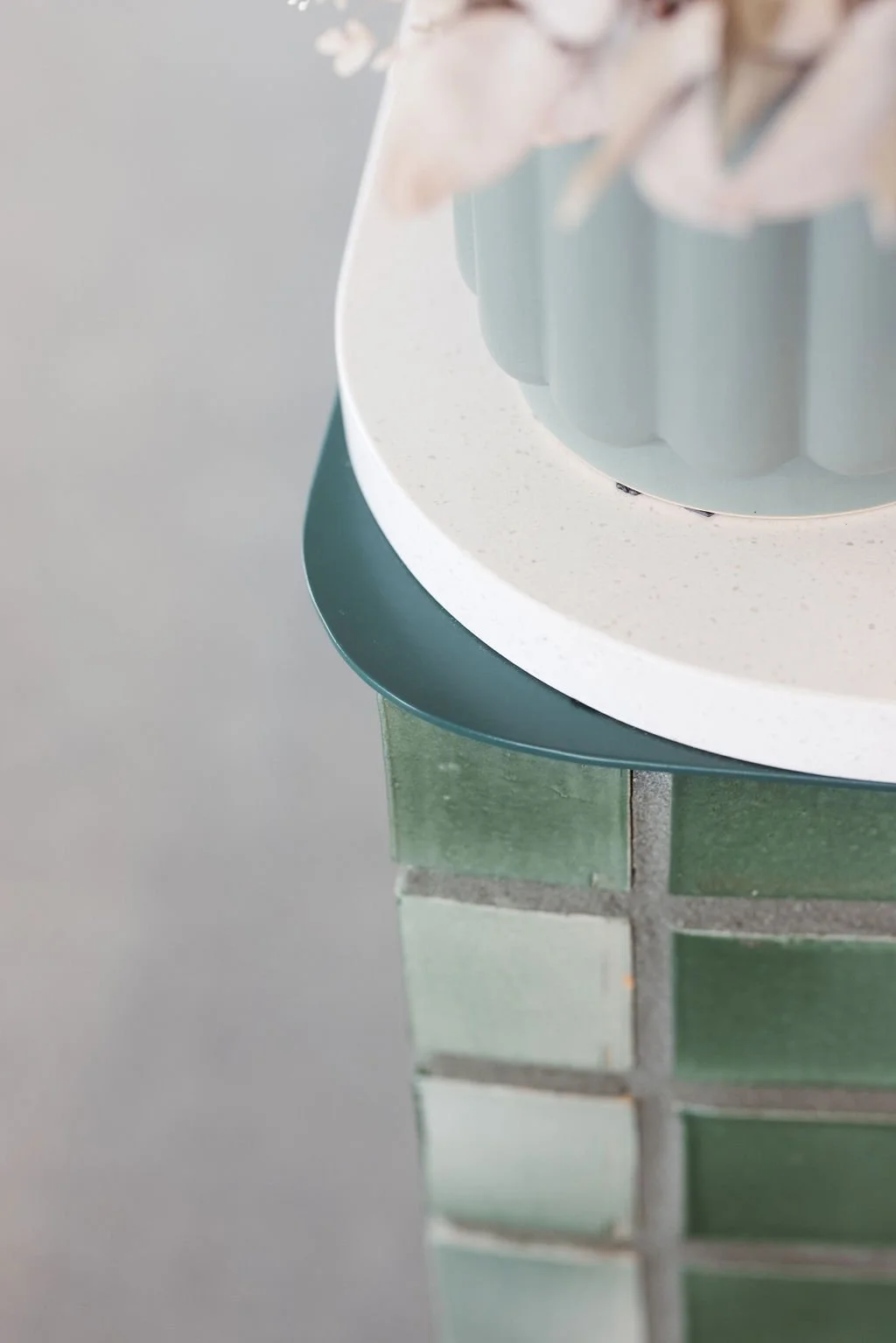 Close-up view of a round table with a white surface and a black and green tiled floor beneath it.