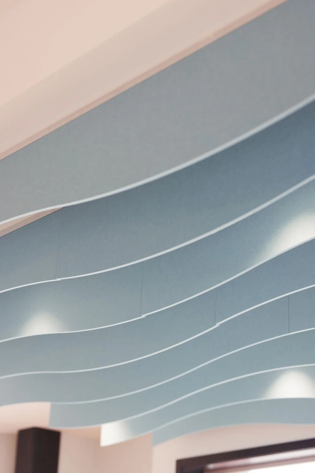 Contemporary ceiling with wavy, layered design and integrated lighting.