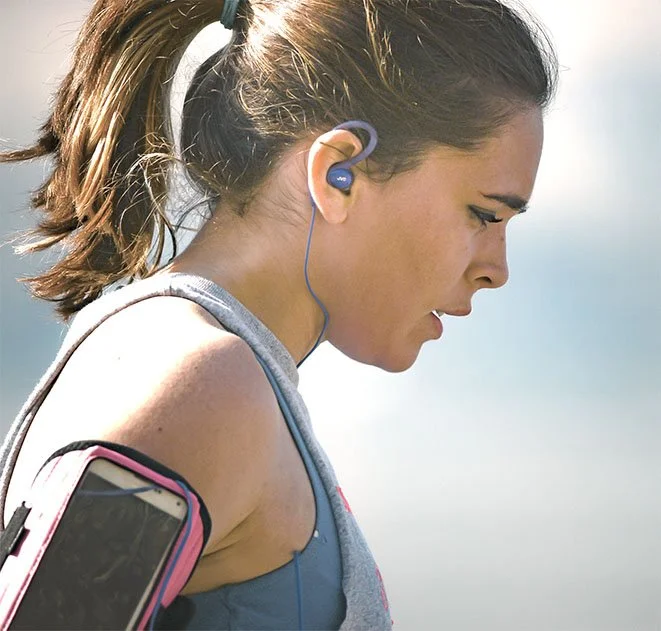 Girl wearing ear buds, breathing hard post-workout