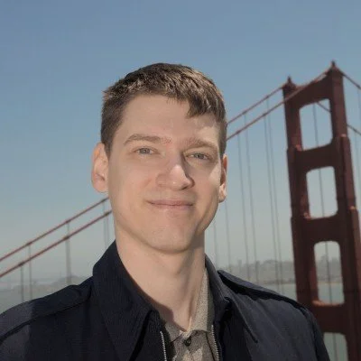 A young man smiling in front of the Golden Gate Bridge in San Francisco