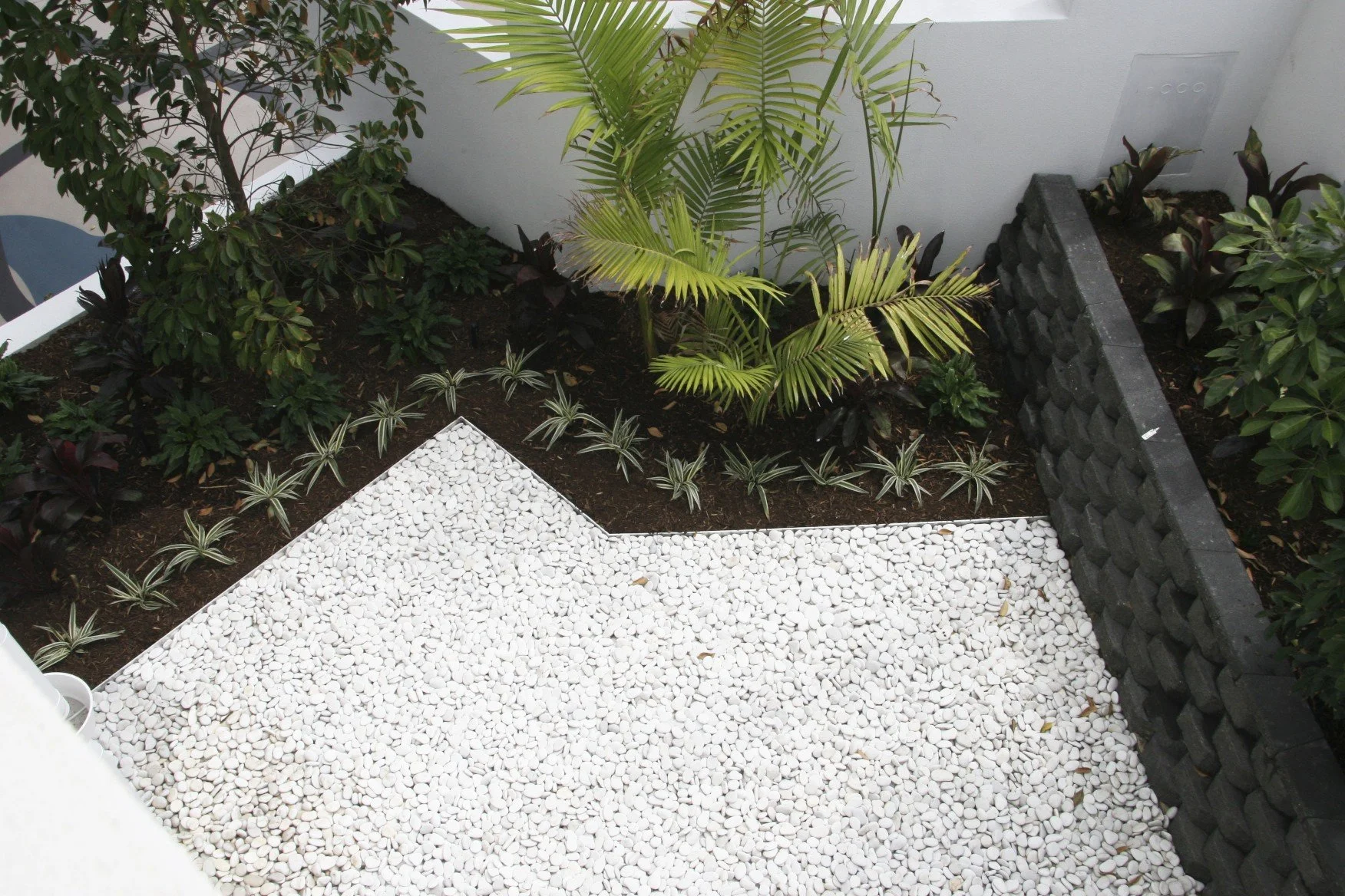 Aluminium landscape edging defining a planted garden bed beside decorative white stone