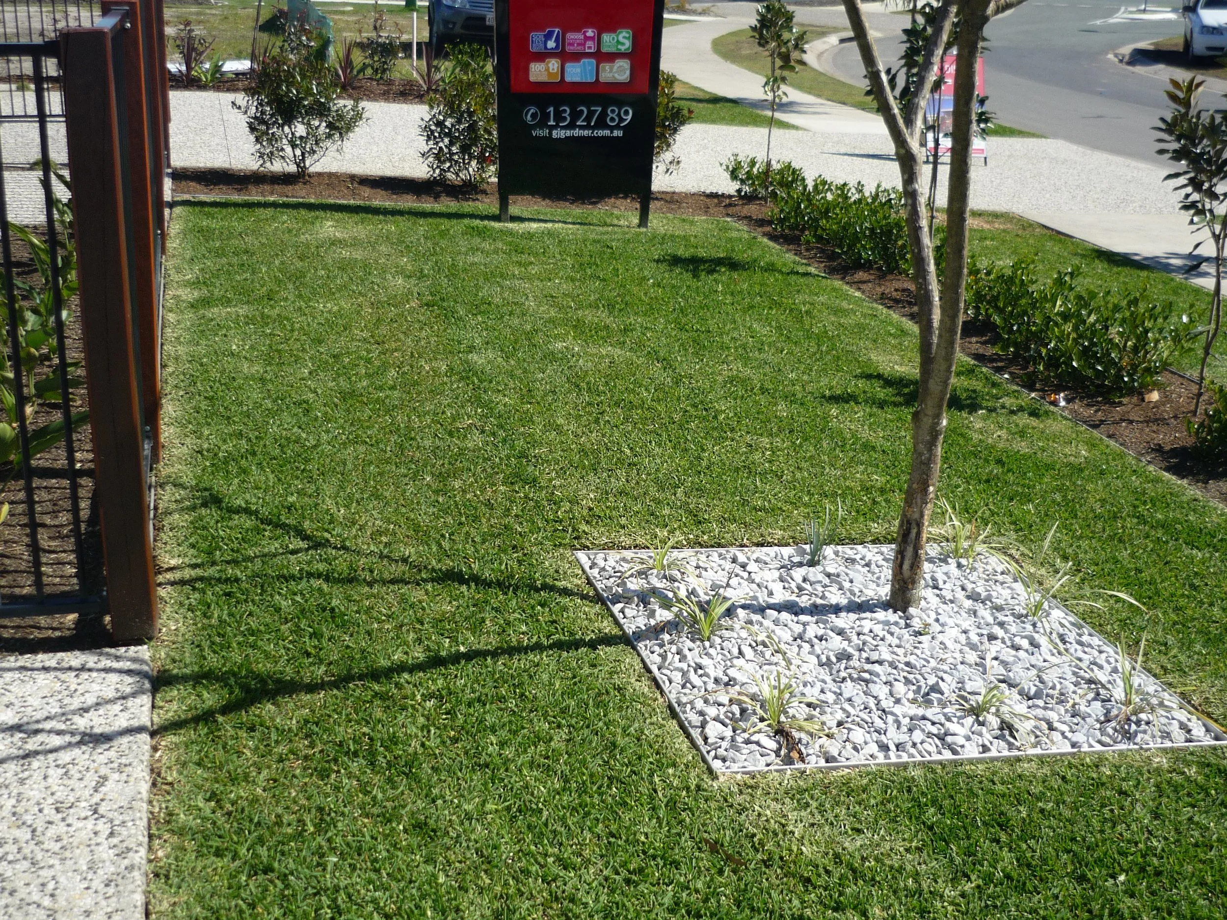 Aluminium landscape edging defining lawn and a decorative stone tree surround