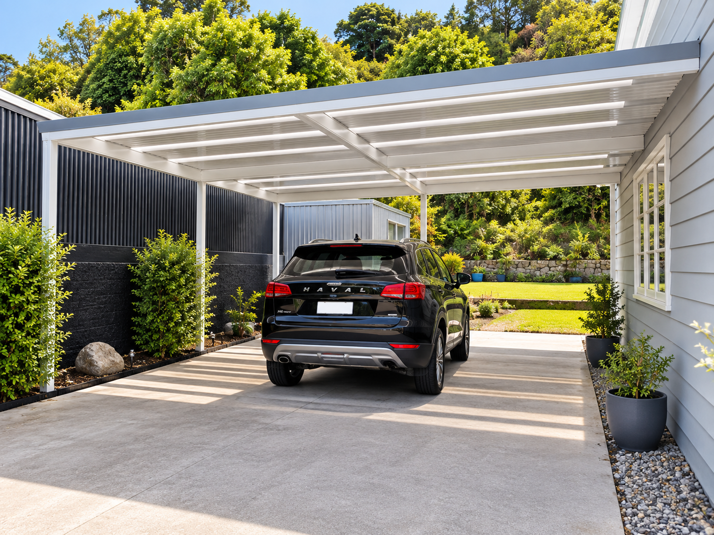 A black Haval SUV parked under a modern white carport with horizontal panels. The carport is supported by white posts and casts striped shadows on the concrete driveway. On the left, there's a row of lush green bushes and rocks, and on the right, a s