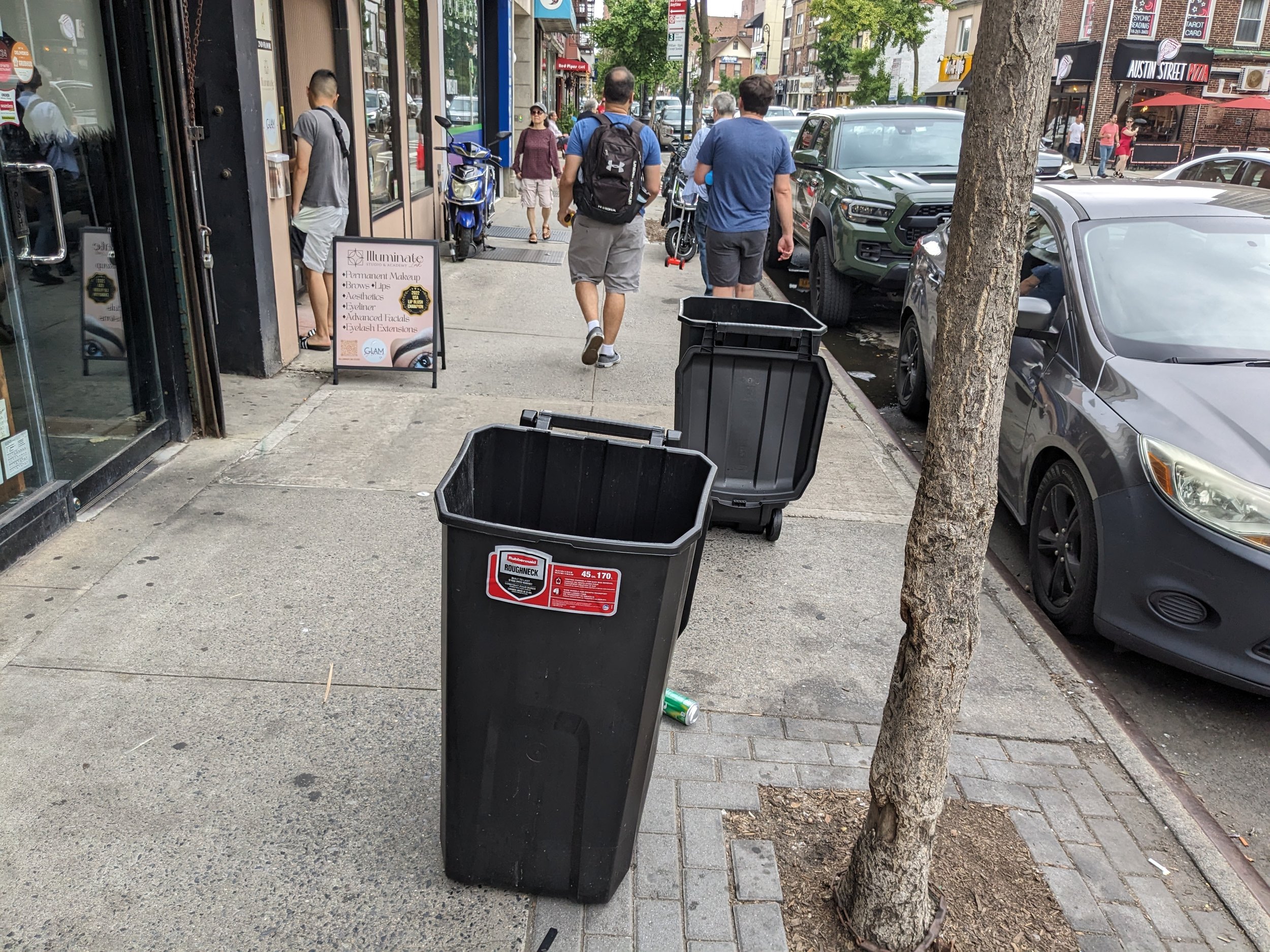 Garbage containers on the sidewalk, inside the clear path.