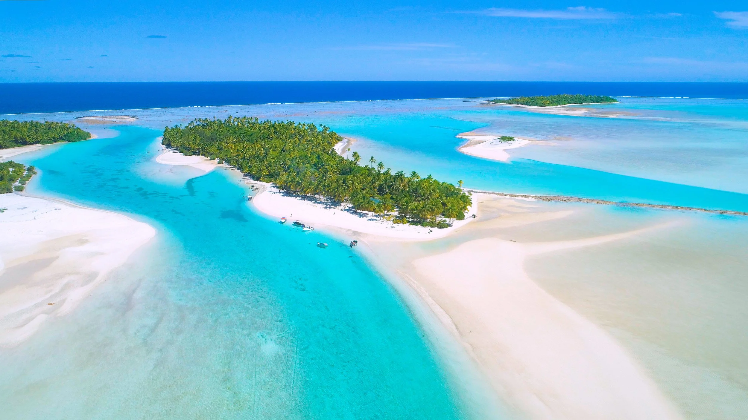 A drone shot of locals having fun in the tranquil turquoise blue ocean of the South Pacific Cook Islands.
