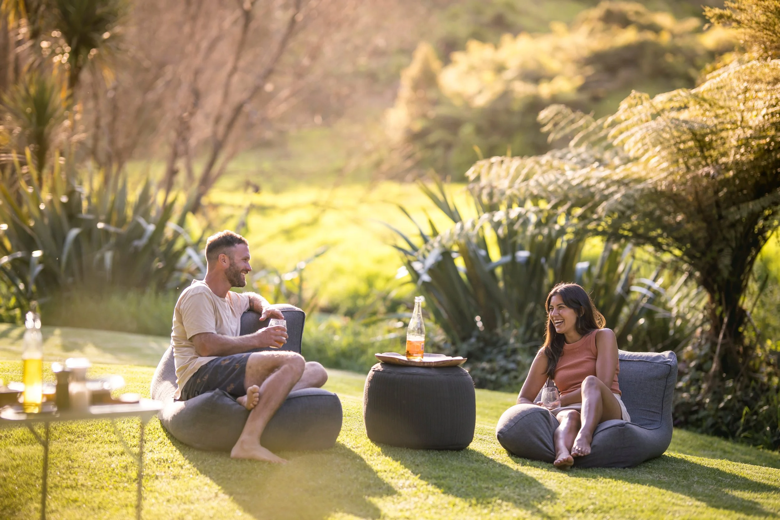 A couple relaxing at a glamping site in Sandy Bay, Matapouri, Northland, New Zealand, surrounded by greenery.