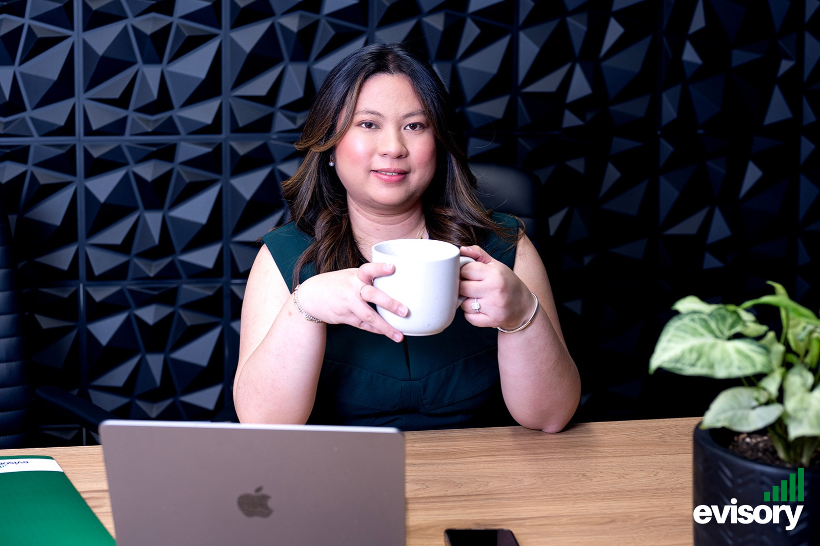 Linda Dang holding a coffee cup at a desk with a laptop, helping hospitality operators understand why venue-specific accounting matters.