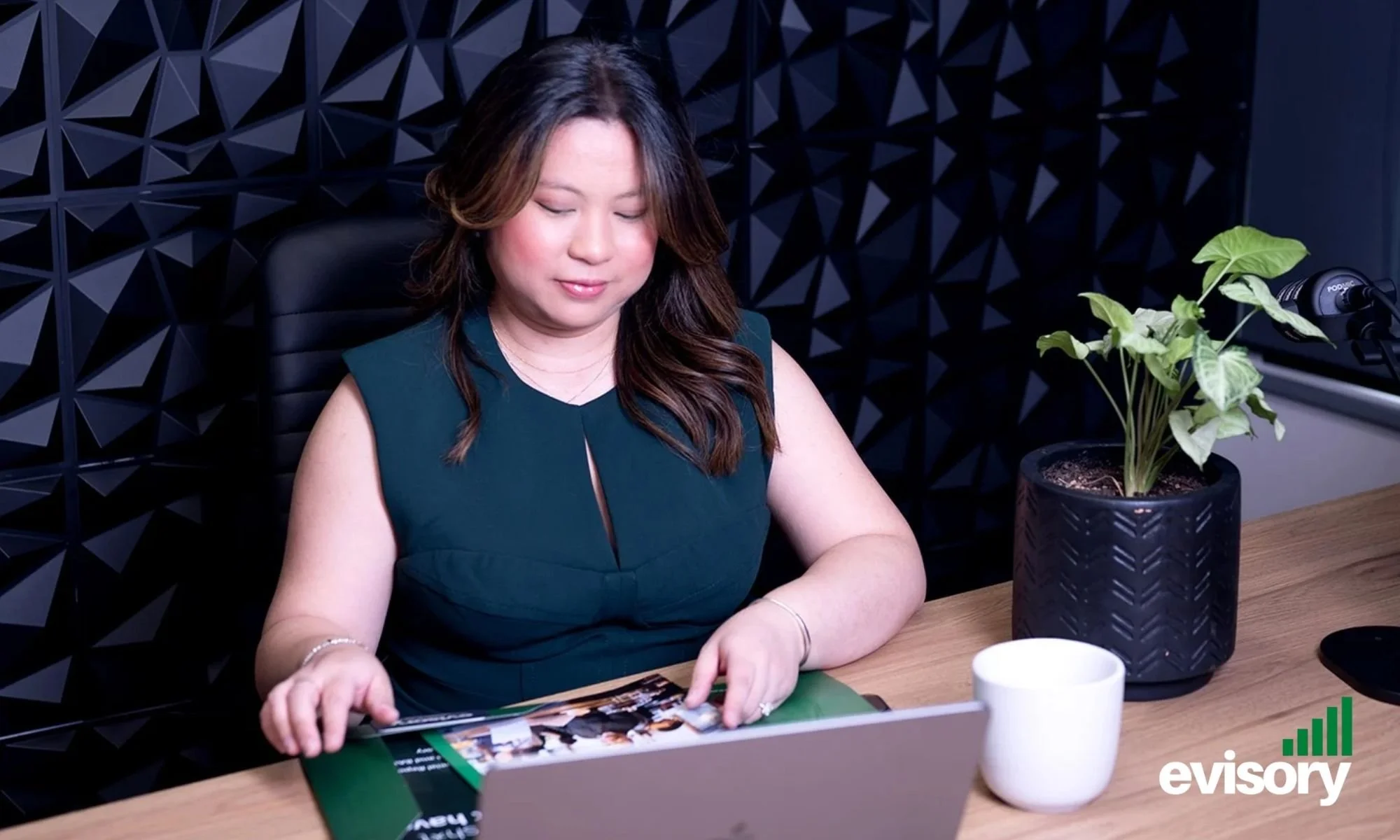 Evisory CEO Linda Dang reviewing financial documents and brochures at a desk.