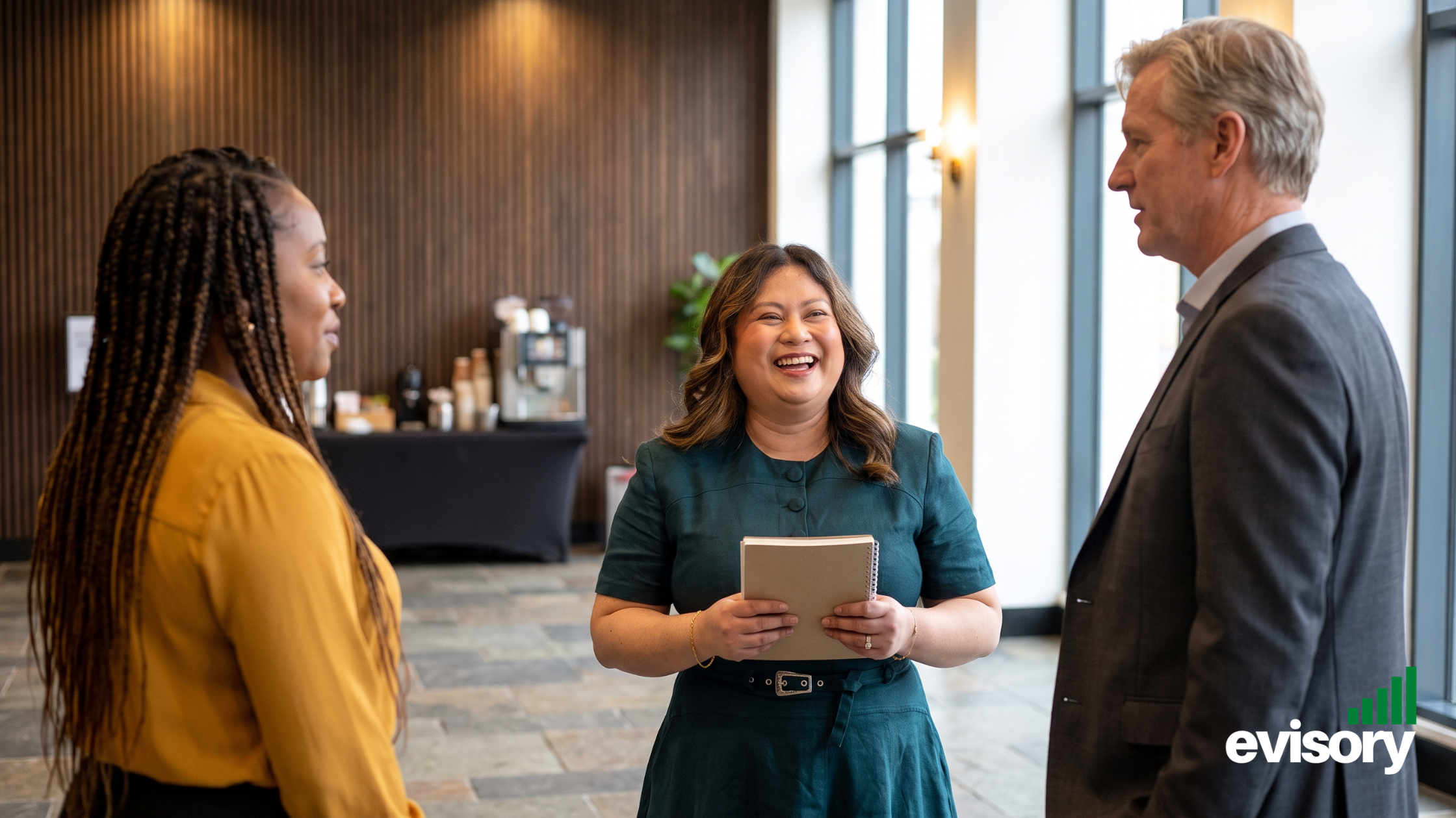 Linda Dang holding a notebook and smiling while speaking with two business clients in a modern function center lobby.