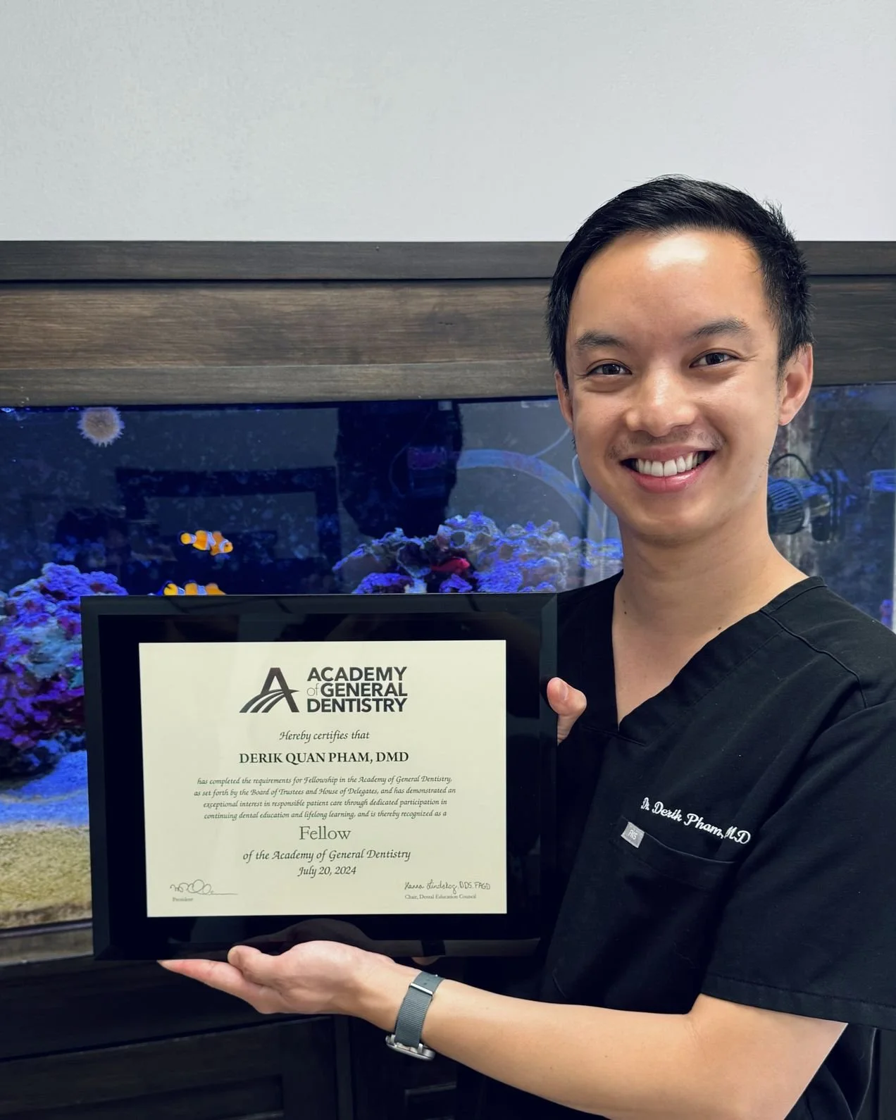 Dr. Derik Pham holding his Fellowship certificate from the Academy of General Dentistry