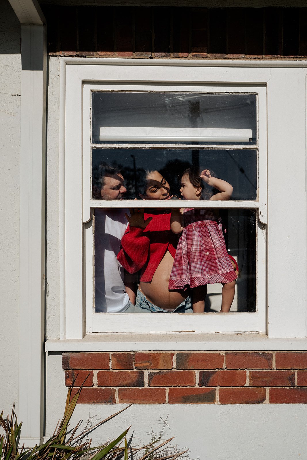 Look at all the ingredients that made up these images....

Their living room window, the sunshine, a sweet bumping belly, that red colour, love and laughter between Mum, Dad and big sister. Nothing else mattered in this moment.

Let's keep your photo