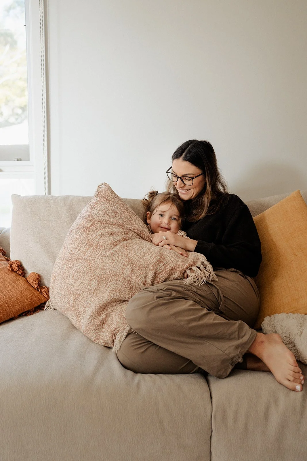 Mother and daughter hugging on the couch during an in-home family photography session in Melbourne.