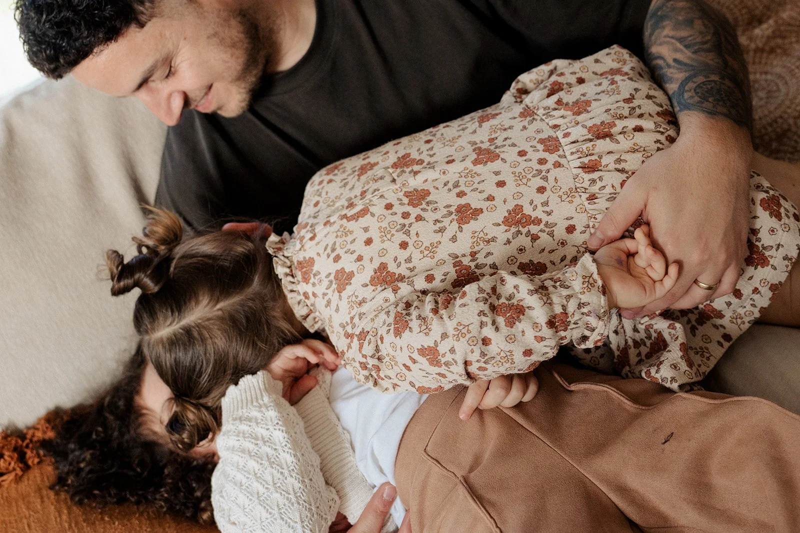 Two sister and a dad playing "stacks on" on their living room couch during an in-home family photography session in Melbourne.