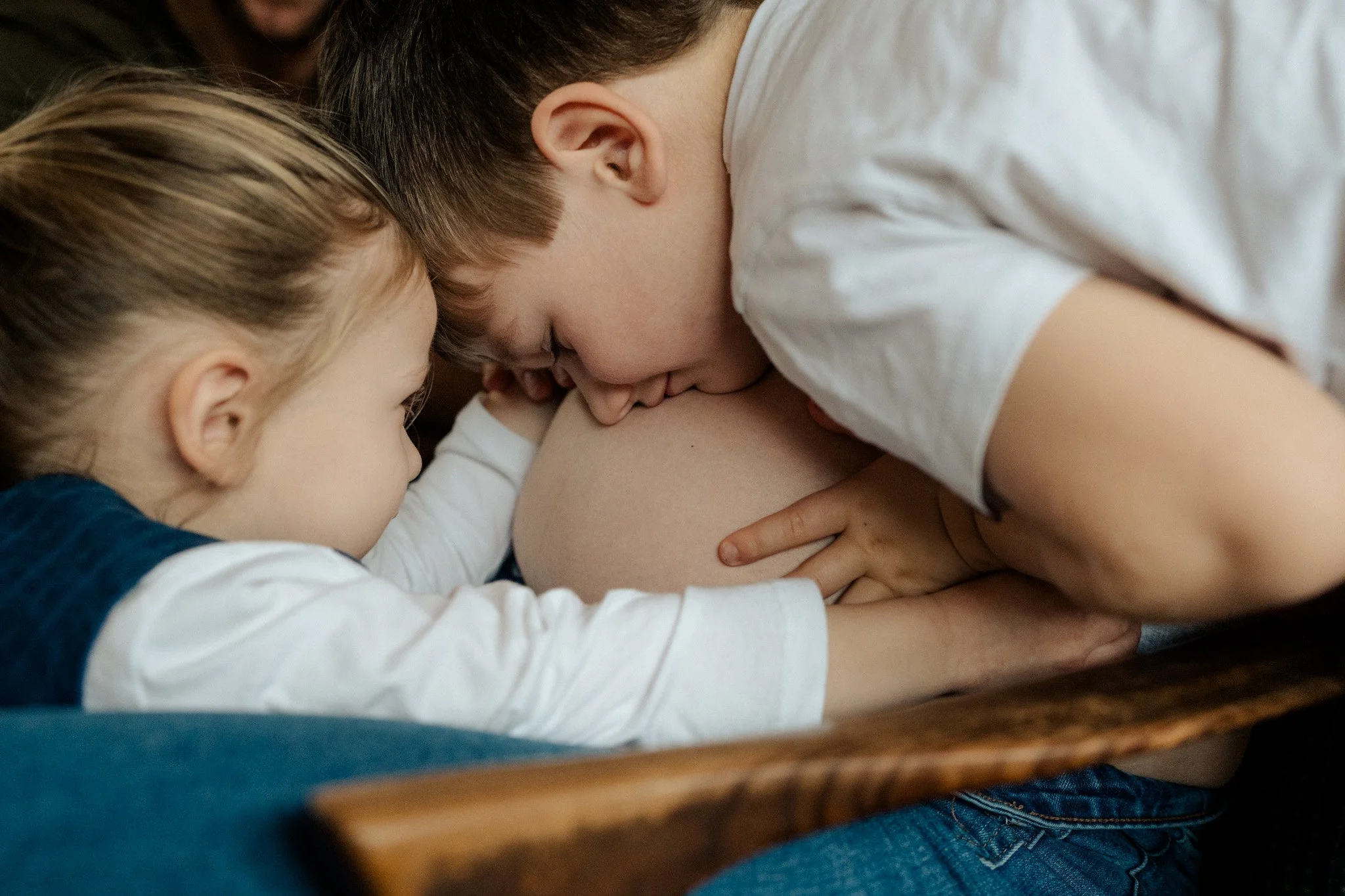 Two kids kissing their pregnant mums tummy during an in-home maternity photography session in Melbourne