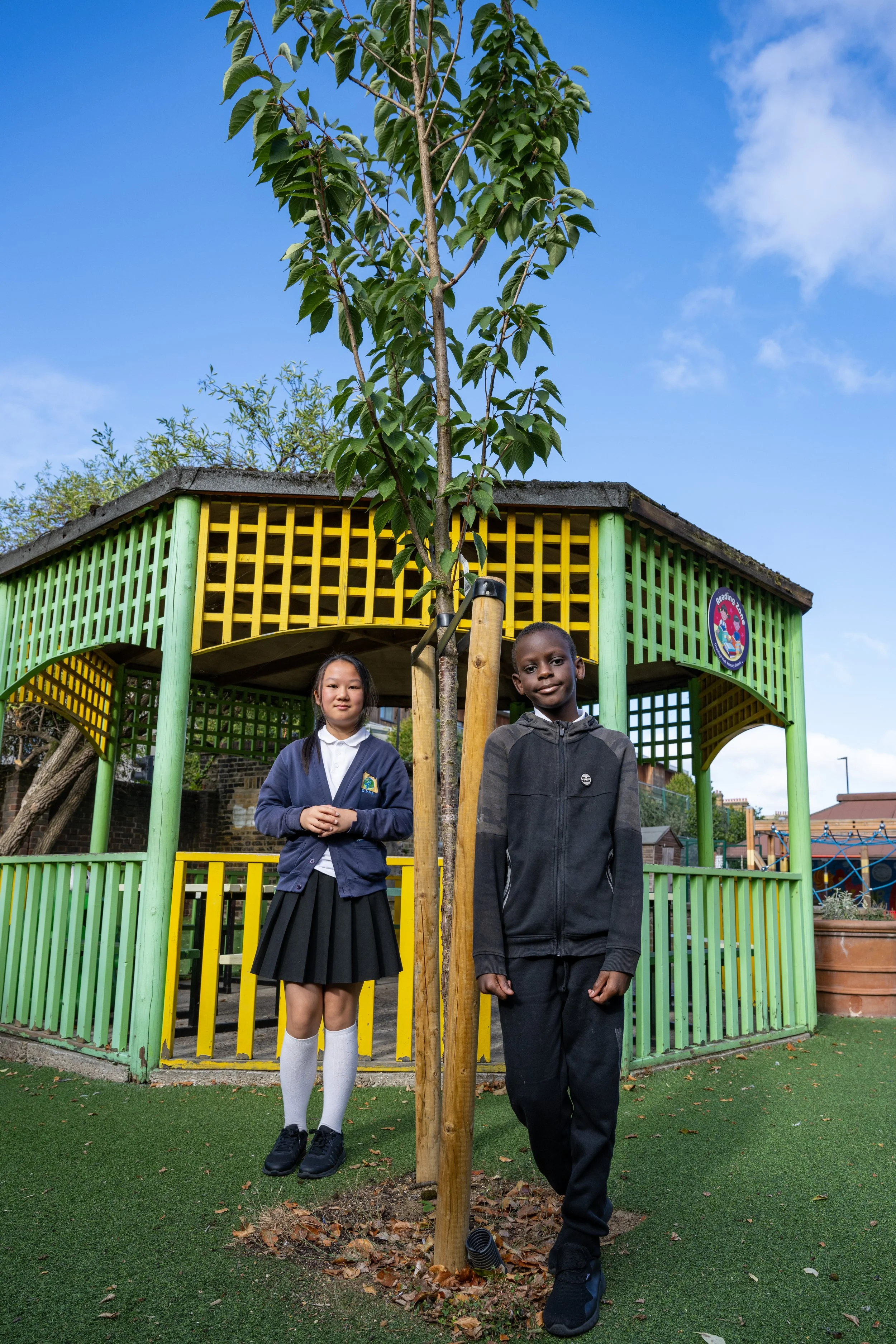 Two kids standing by planted tree.jpg