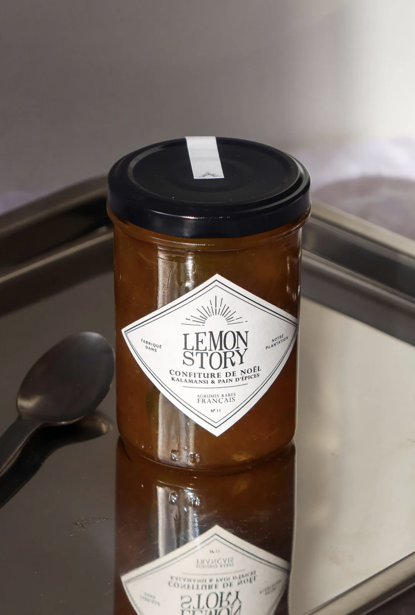 Un pot de confiture Lemon Story sur un plateau avec une cuillère.