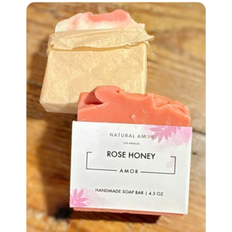 A handmade soap bar labeled "Rose Honey" with pink and beige-colored soap pieces on a wooden surface.