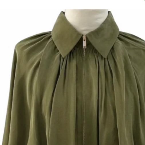 A green garment with a collar and zipper, likely a cape or cloak displayed on a mannequin.