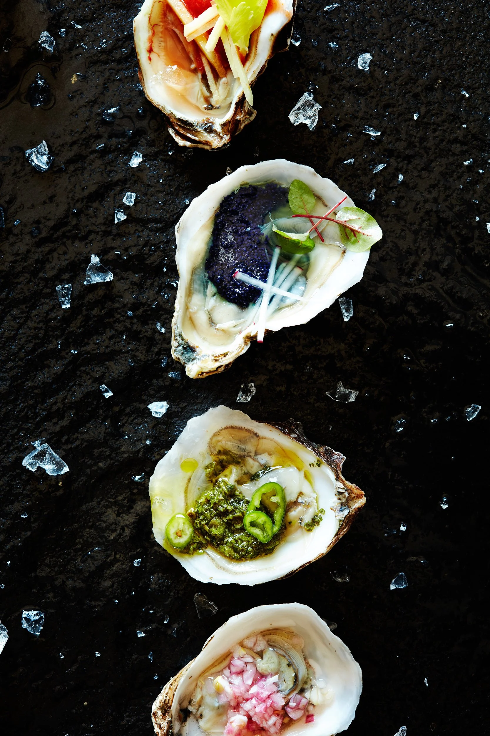 Four raw oysters with different flavour combinations on top, Bloody Mary, caviar, Chimichurri, mignonette - for a test concept shoot and photographed by Cheng Li - food styling, commercial food stylist NYC