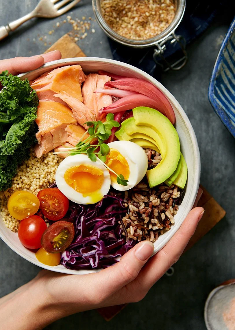 A wellness bowl of kale, quinoa, smoked salmon and trout, pickled red onions, avocado, soft boiled egg and cous cous and rice - for a test concept shoot and photographed by Cheng Li - food styling, commercial food stylist NYC
